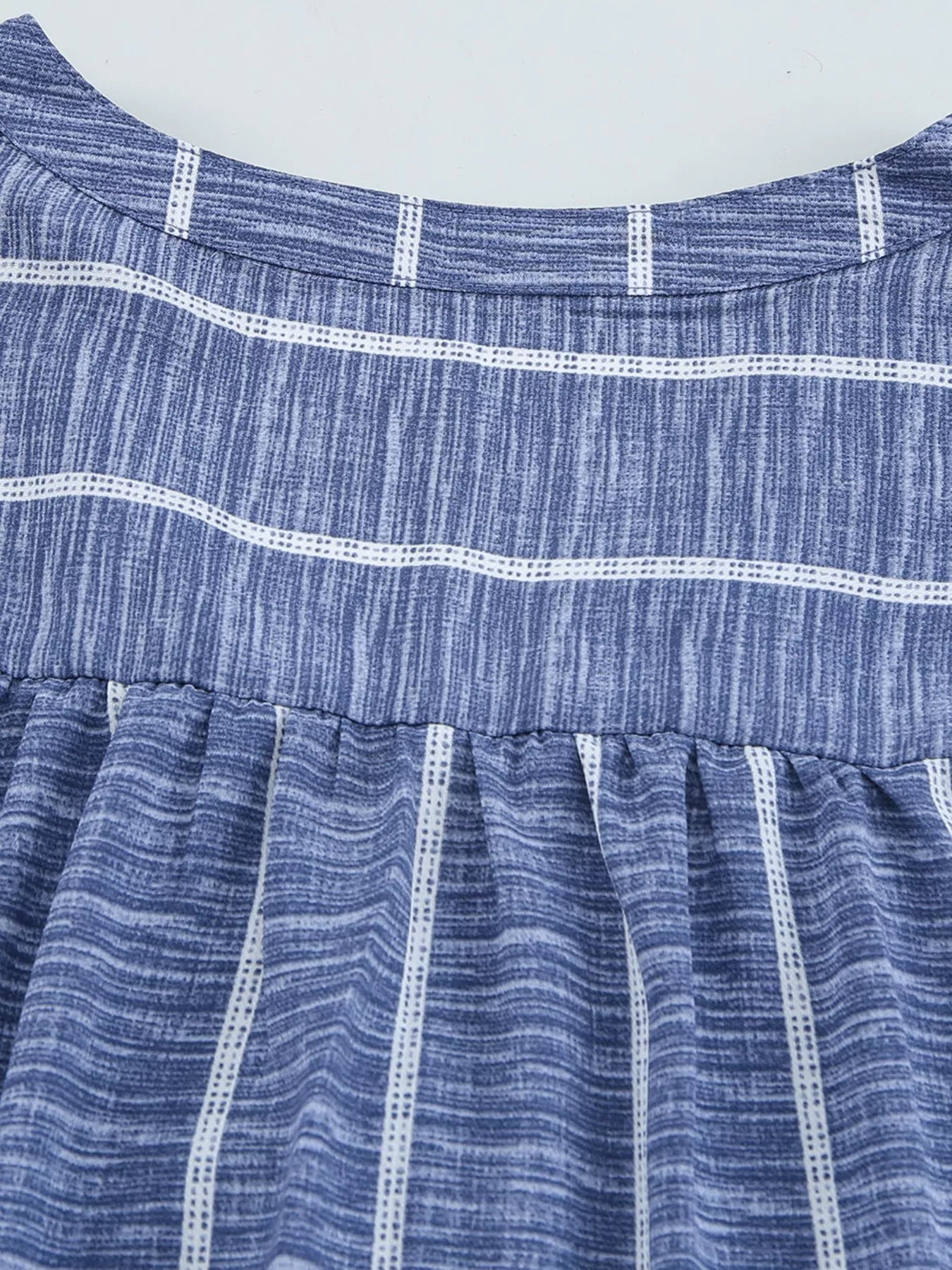 Dusty blue striped V-neck blouse with a buttoned front and gathered waist detail.