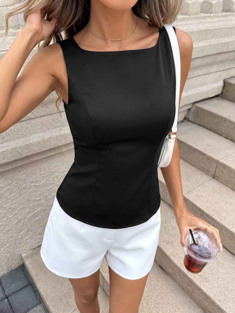 Black fitted sleeveless blouse with boat neckline and subtle back cutout detail.