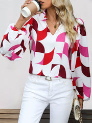 Geometric print blouse in white with pink and red shapes, featuring voluminous sleeves and a V-neck.