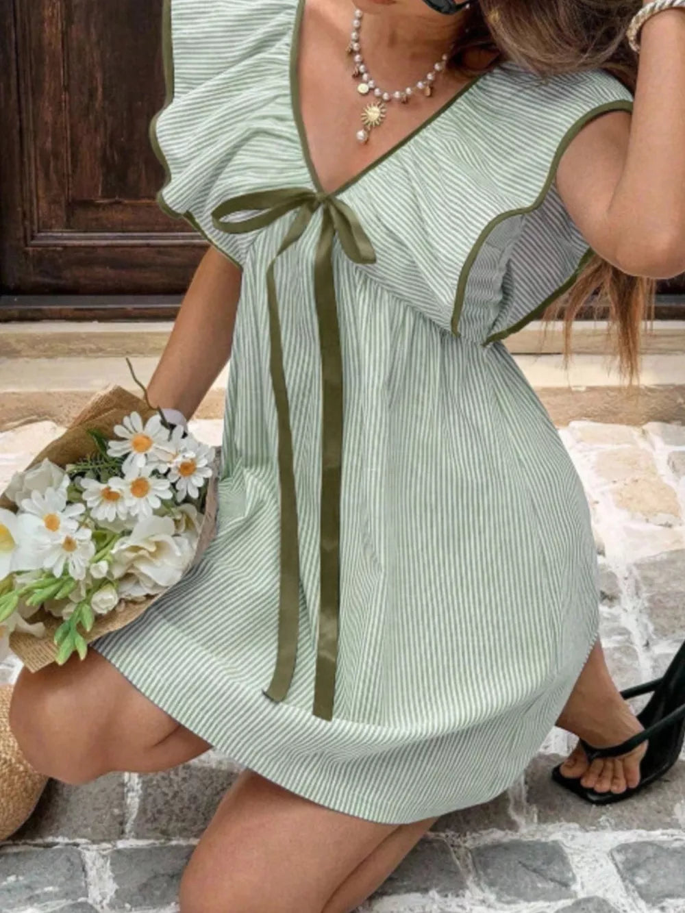 Green striped mini dress with ruffled sleeves, V-neck, and bow detail.