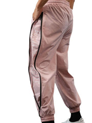 Dusty pink track pants with full-length side zippers and reflective logo detail.