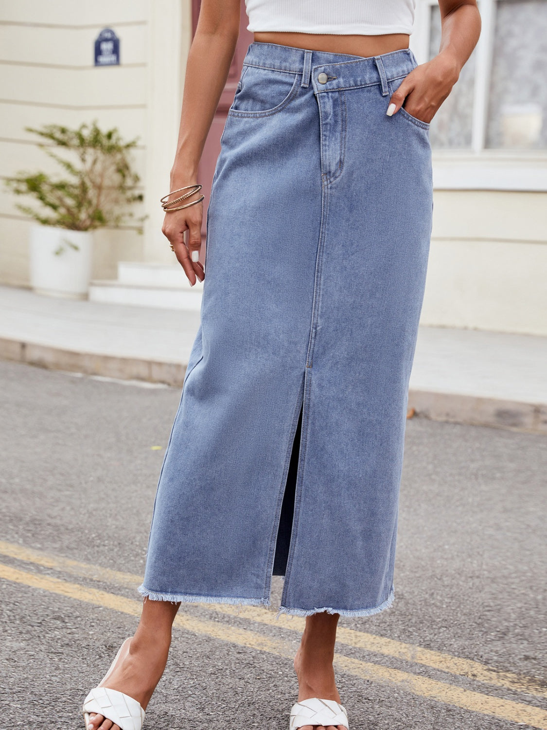 Light denim midi skirt with asymmetric front slit and frayed hem.