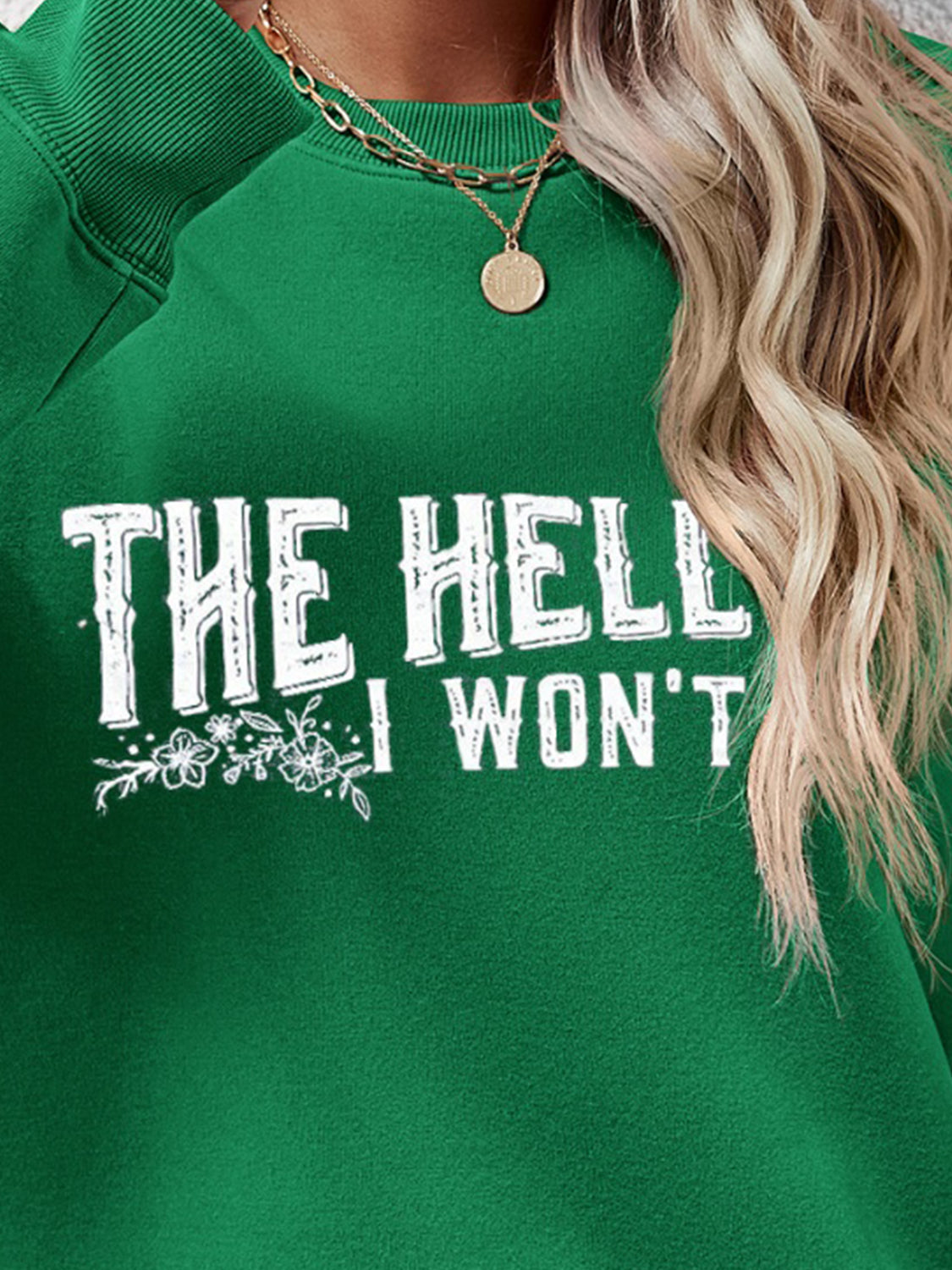 Green crewneck sweatshirt with white graphic text and floral detail.