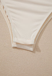 Ivory sequin wrap bodysuit detail showing snap closure and fabric texture.
