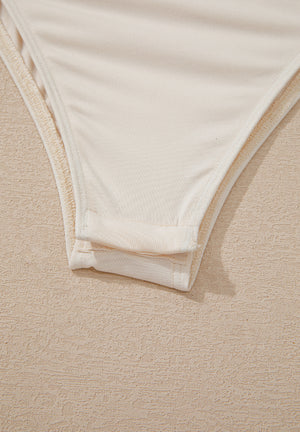 Ivory sequin wrap bodysuit detail showing snap closure and fabric texture.