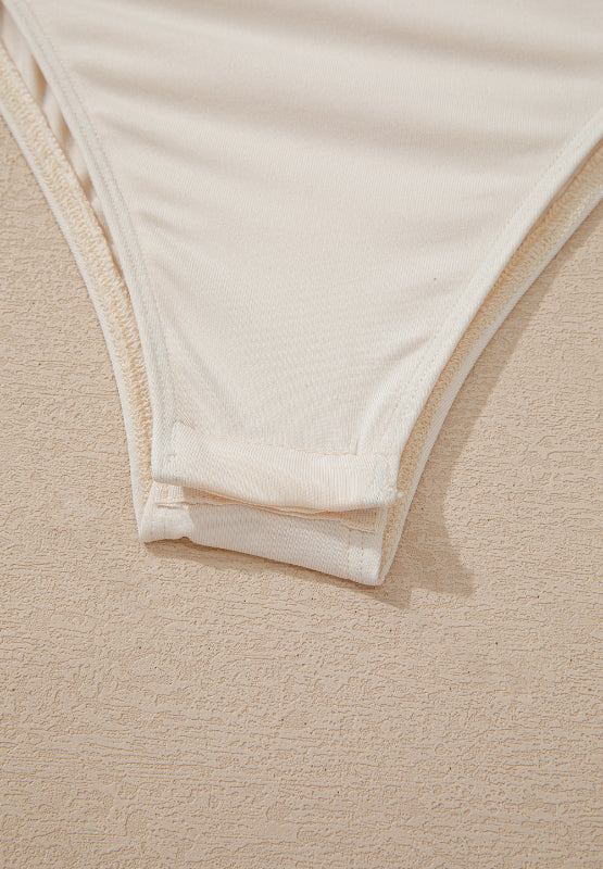 Ivory sequin wrap bodysuit detail showing snap closure and fabric texture.