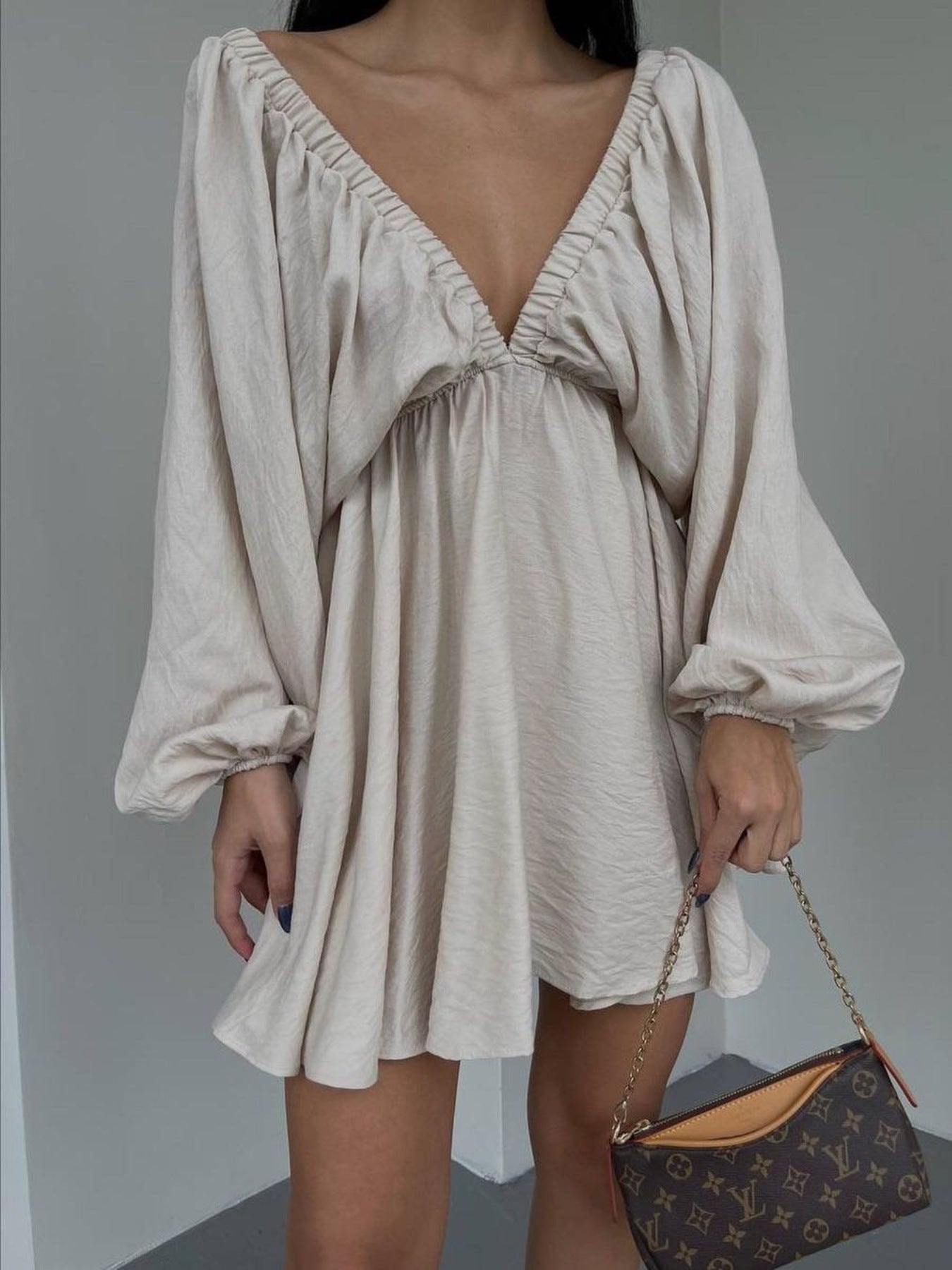 Beige ruched V-neck dress with balloon sleeves and cinched cuffs.