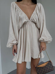 Beige ruched V-neck dress with balloon sleeves and cinched cuffs.