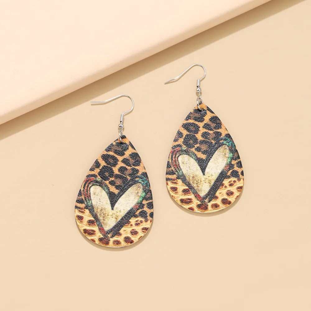 Leopard print teardrop earrings with a distressed heart detail and silver hooks.