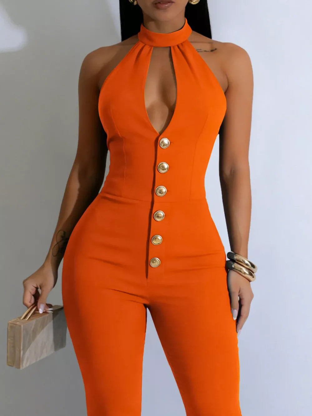 Orange halter cut-out jumpsuit with gold buttons and a high neckline.