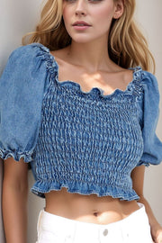 Smocked denim crop top with ruffled square neckline and puff sleeves.