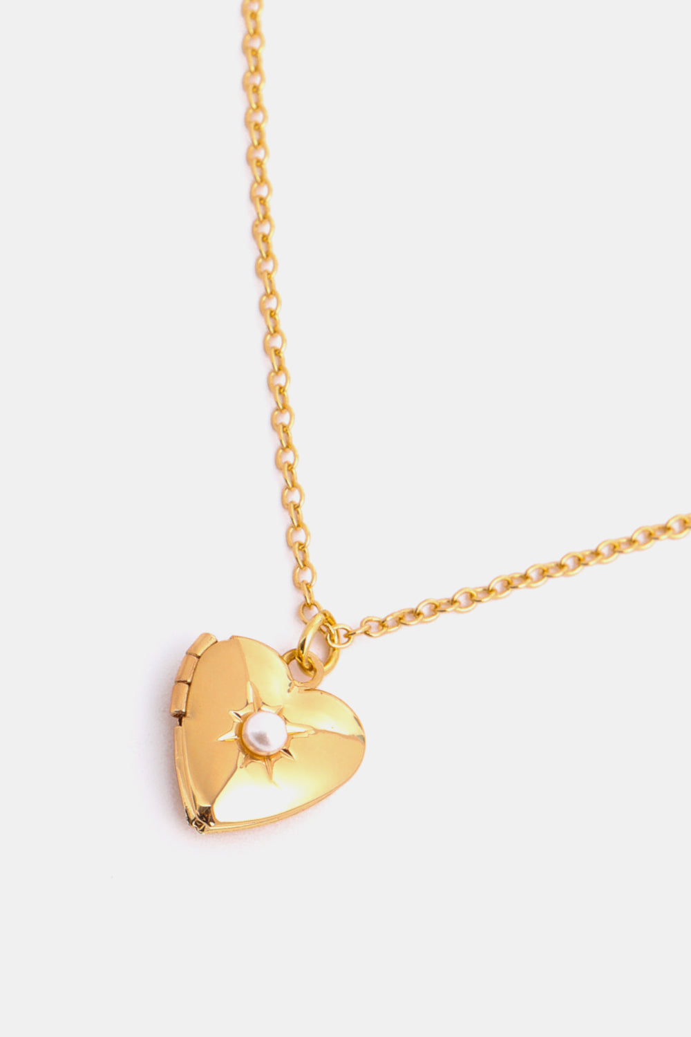Gold heart locket necklace with pearl detail and chain.