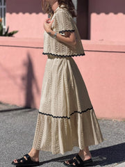 Cream crochet co-ord set with scalloped black trim, featuring a cropped top and maxi skirt.