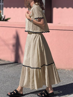 Cream crochet co-ord set with scalloped black trim, featuring a cropped top and maxi skirt.