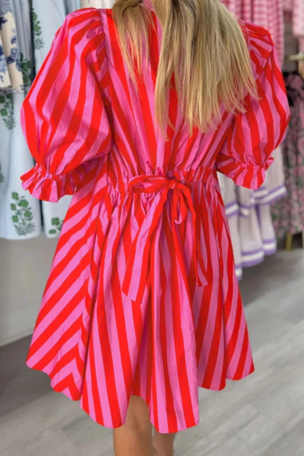 Mini dress with puff sleeves, ruffles, and a tie waist in bold red and pink stripes.