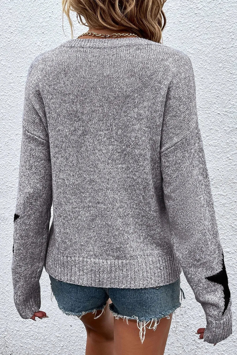 Gray knit jumper with black star details on sleeves, crew neck, long sleeves.