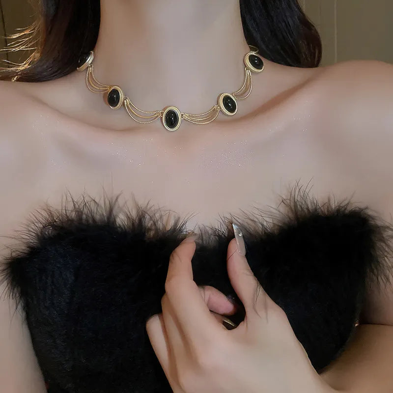 Gold necklace with oval black gemstones and delicate chains