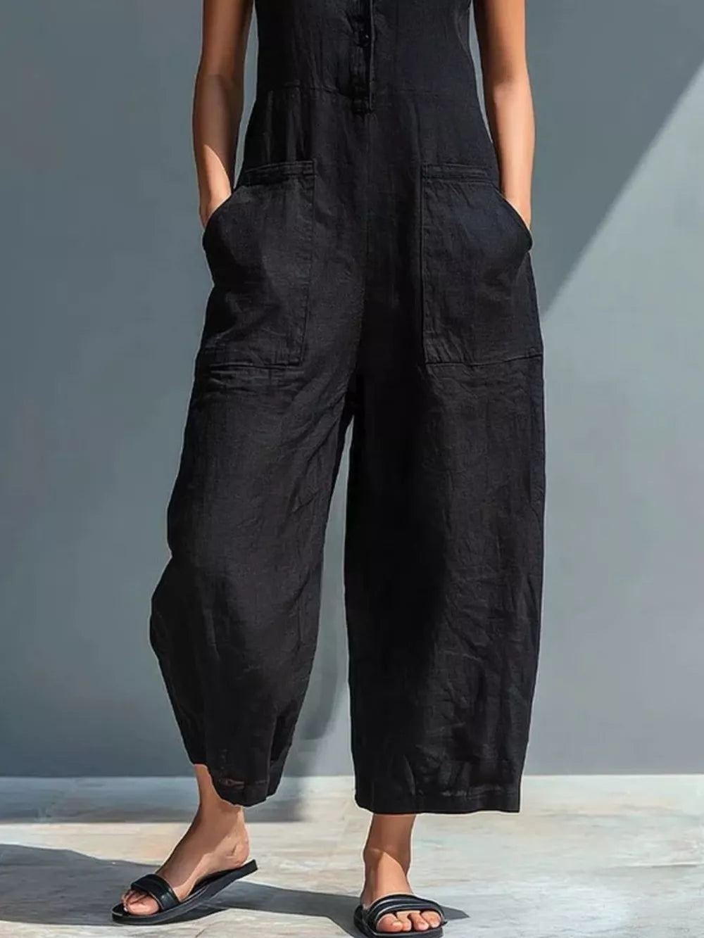 Black button-down sleeveless romper with wide legs and large front pockets.