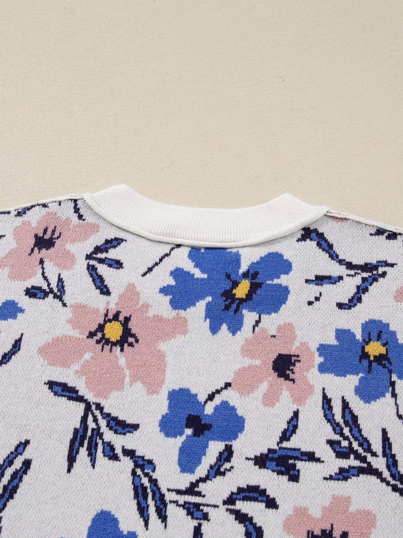 Patchwork sweater with a floral design in pink and blue on white, featuring a ribbed crew neck.