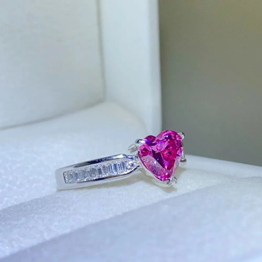 Silver ring with a bright pink heart-cut gemstone and baguette accents.