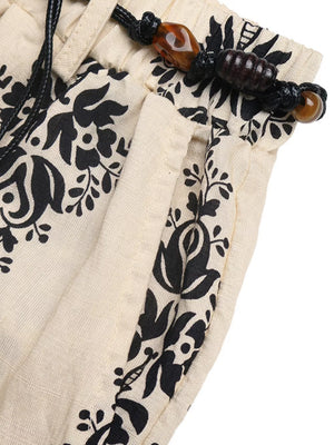 Bohemian beige wide leg maternity pants with black floral print and beaded drawstring.