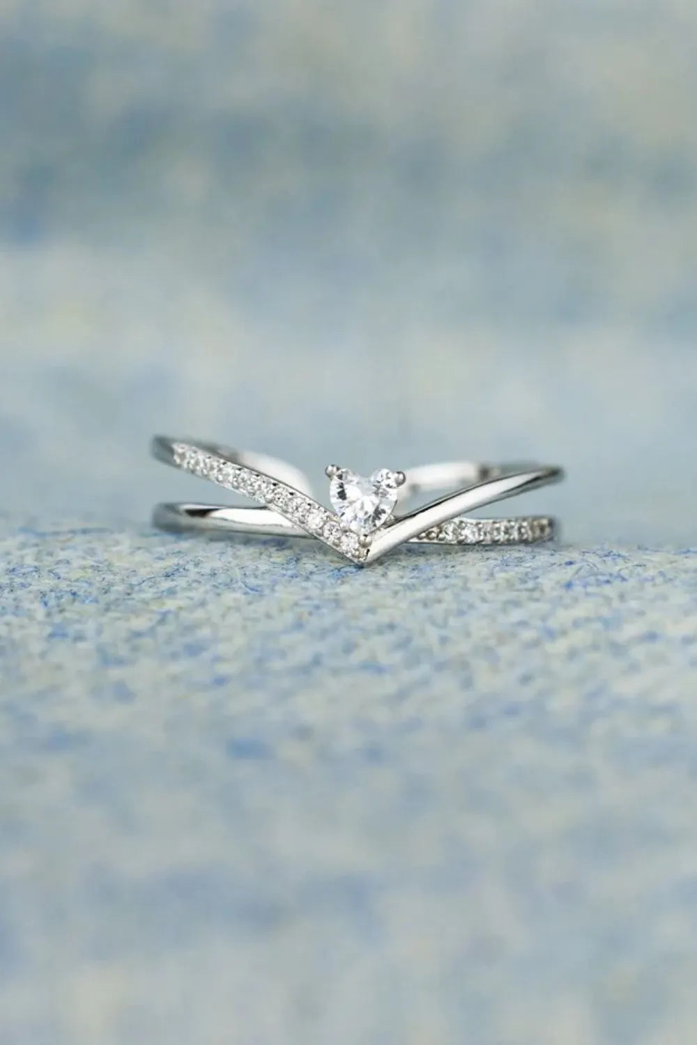 Silver V-shaped ring with diamond accents and a heart-shaped center stone.