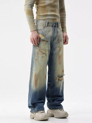 Men's distressed wide-leg jeans in blue denim with heavy fading and rips.