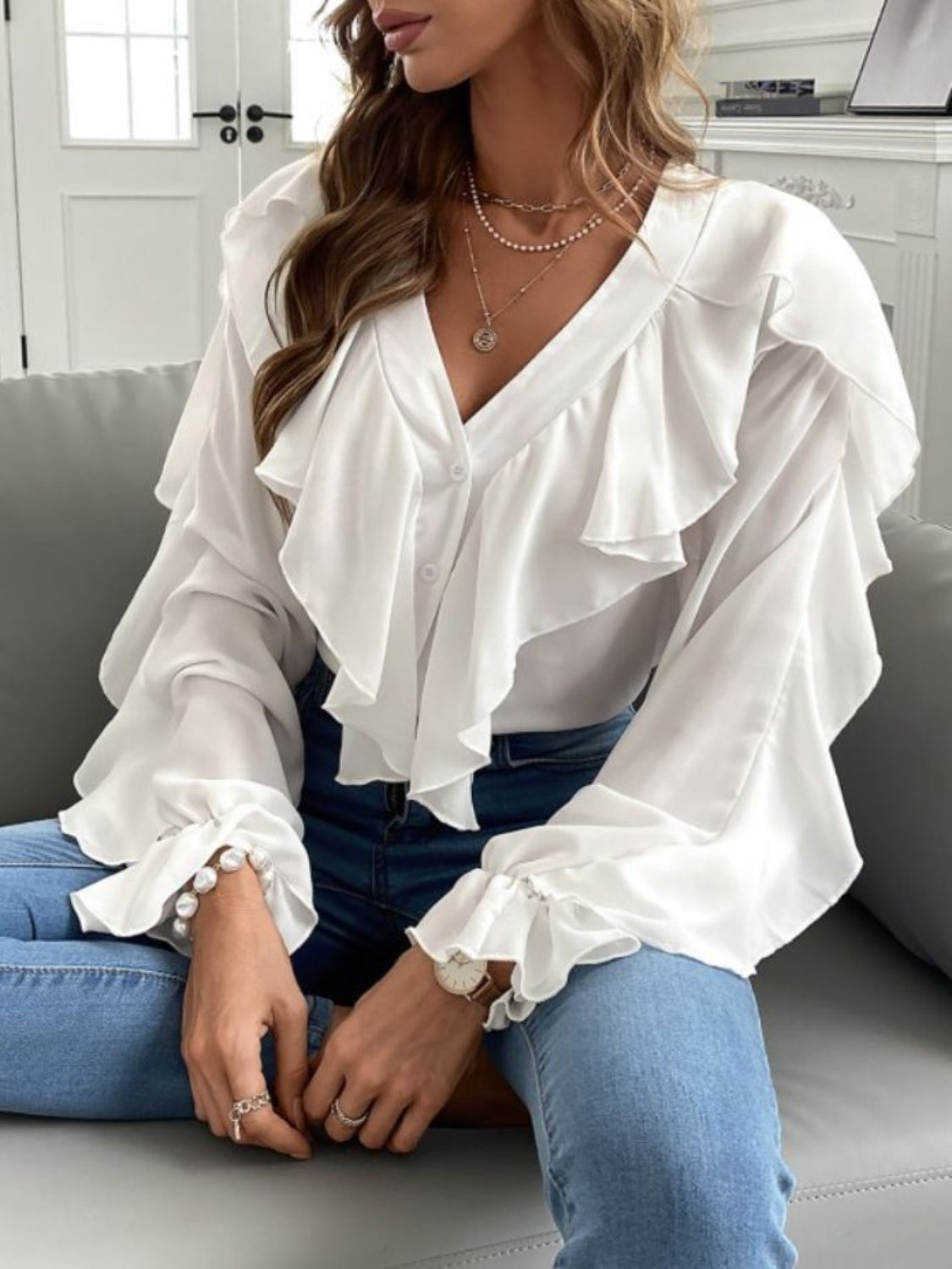 White V-neck blouse with cascading ruffles and bell sleeves.