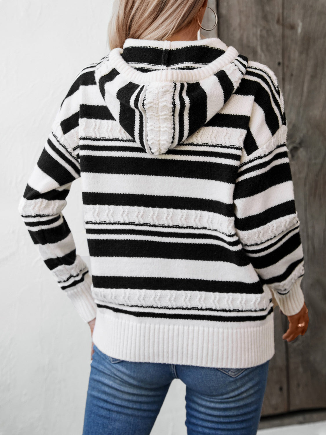 Black and white striped knit hoodie with textured details and ribbed cuffs.