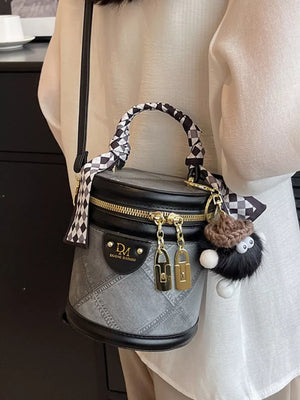Quilted mini bucket bag in grey with black trim, checkered scarf detail and fuzzy charm.