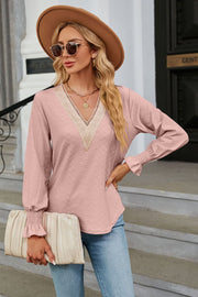 Blush pink textured V-neck blouse with lace trim and smocked cuffs.