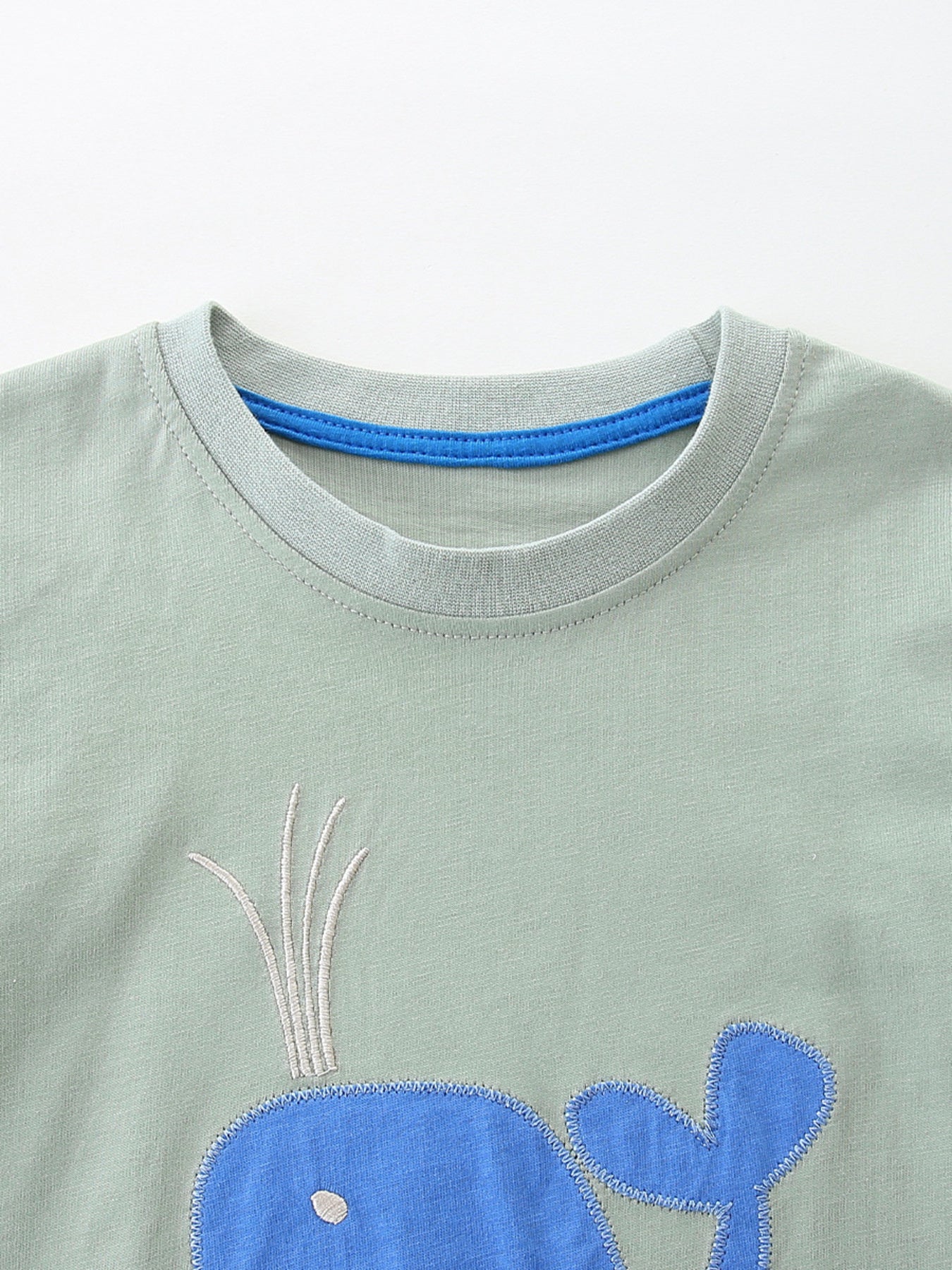 Light green cotton toddler tee with blue whale embroidery and blue neck trim.