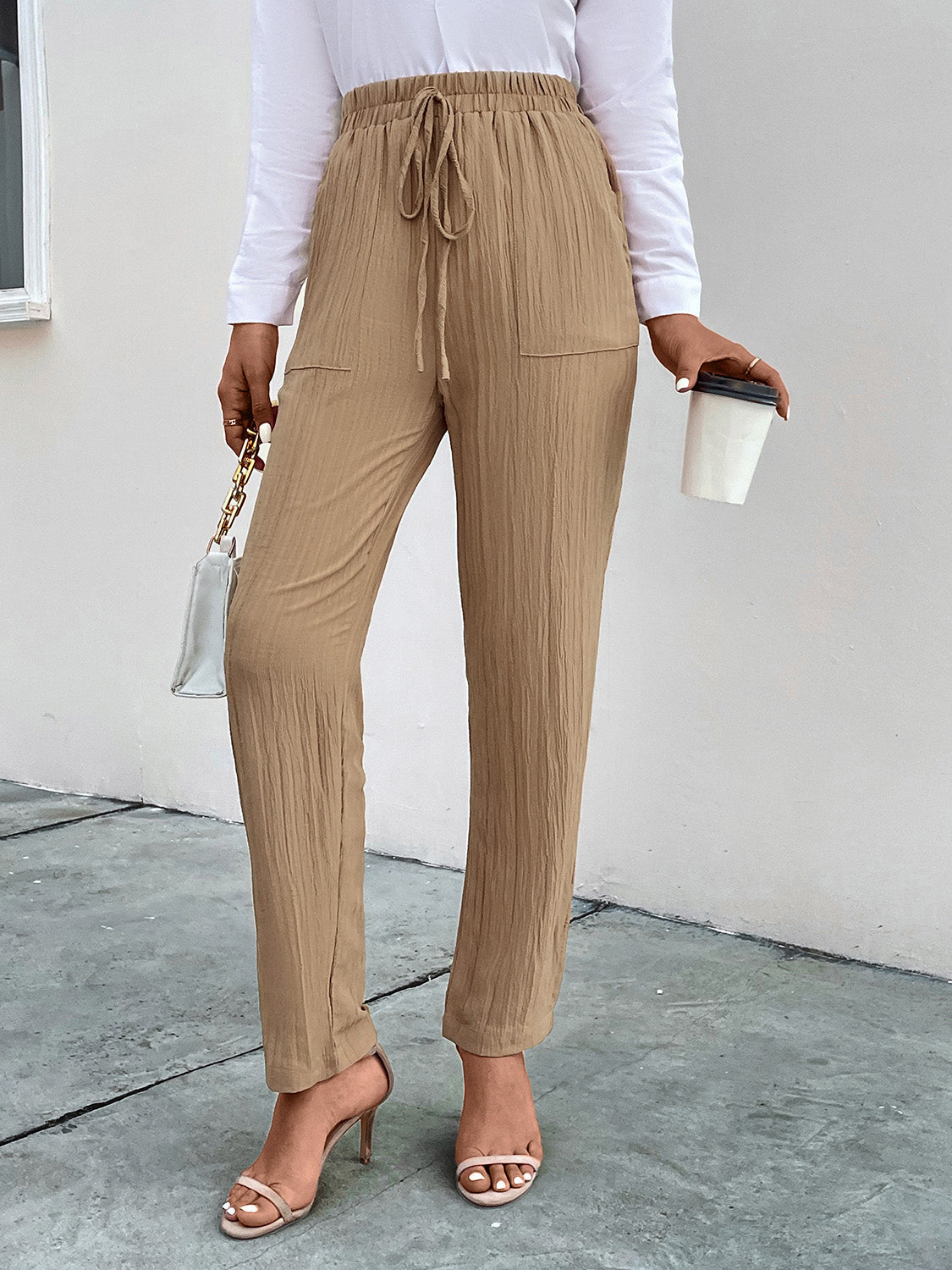 Tan textured tapered trousers with drawstring waist and pockets.