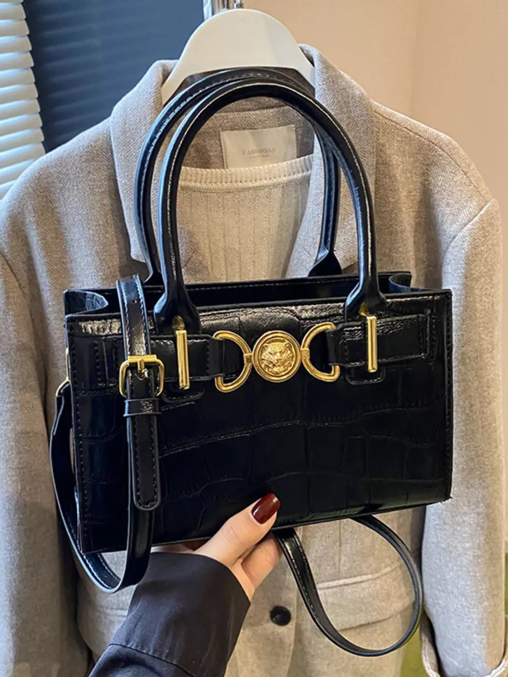Black crocodile-textured crossbody bag with gold hardware and top handles.