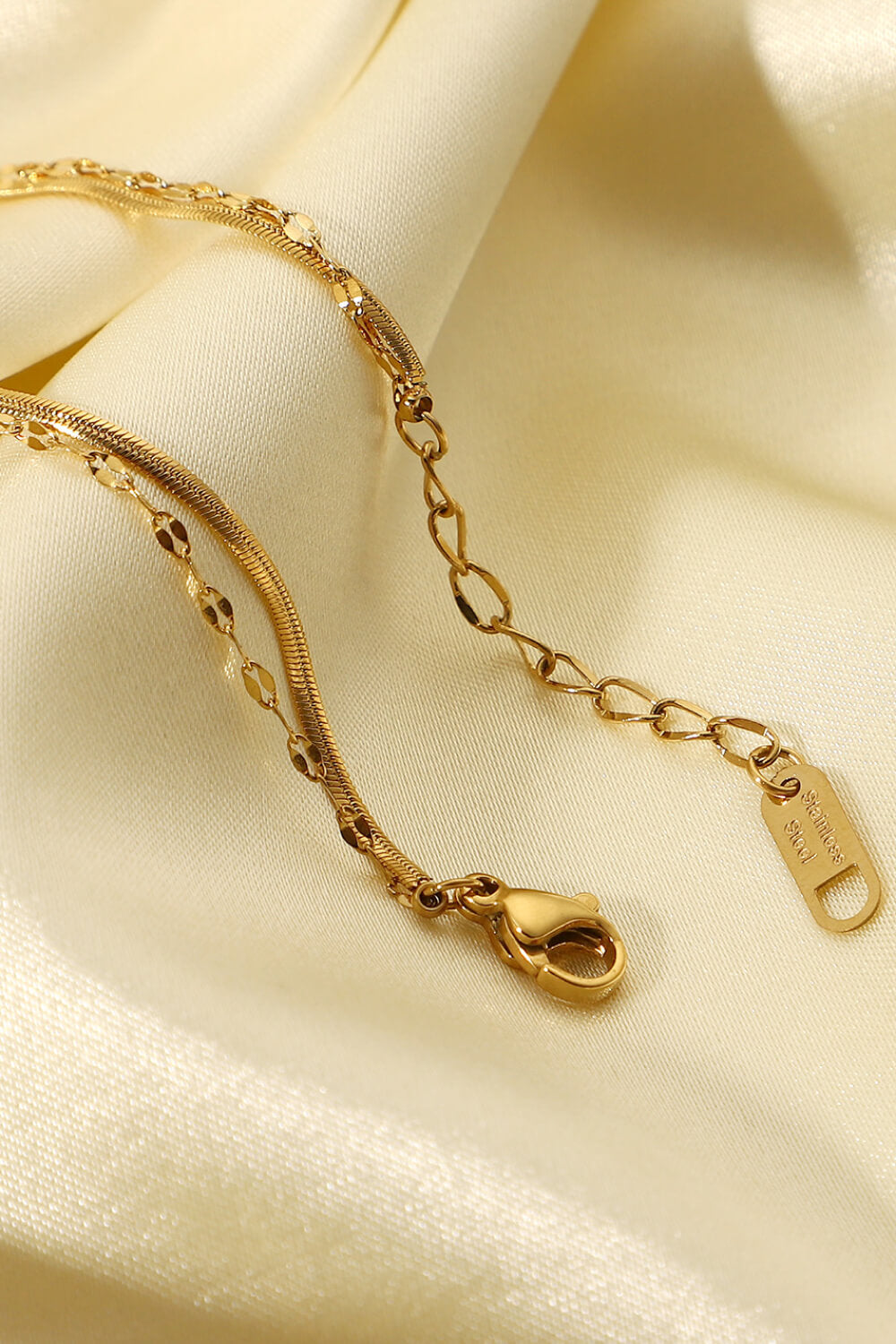 Gold double-strand pavé charm bracelet with snake and link chains and lobster clasp.