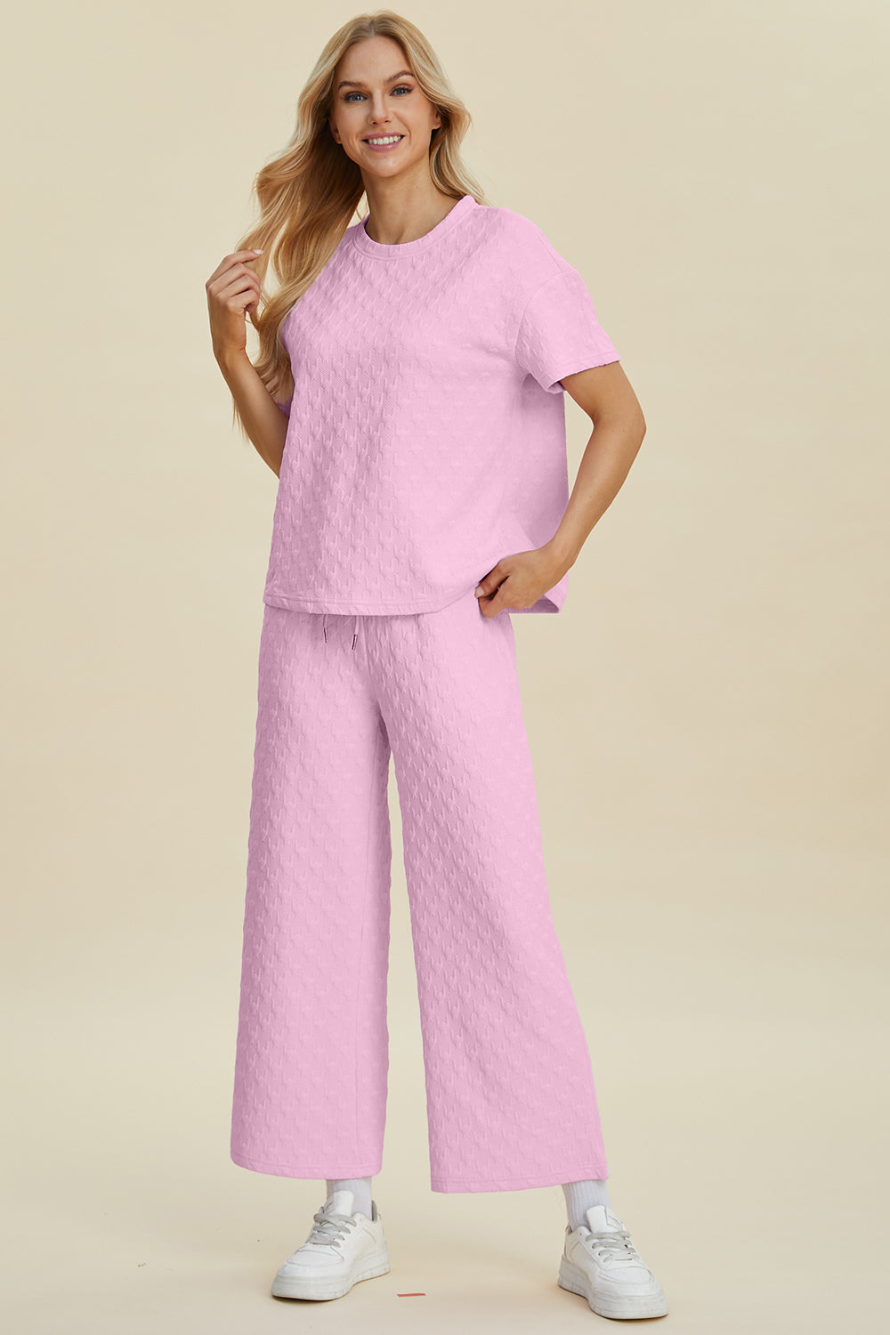 Pink textured knit lounge set with wide leg pants and short sleeve top.