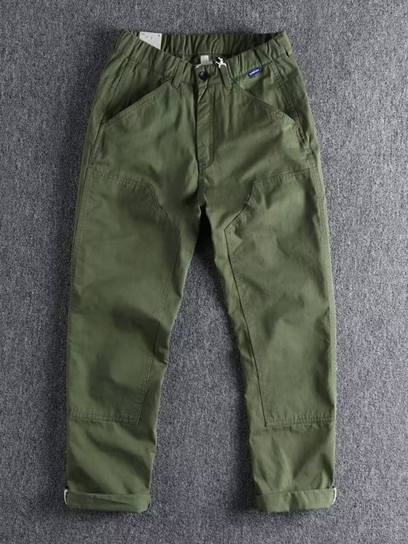 Men's green elastic waist cargo pants with button closure and cuffed hems.