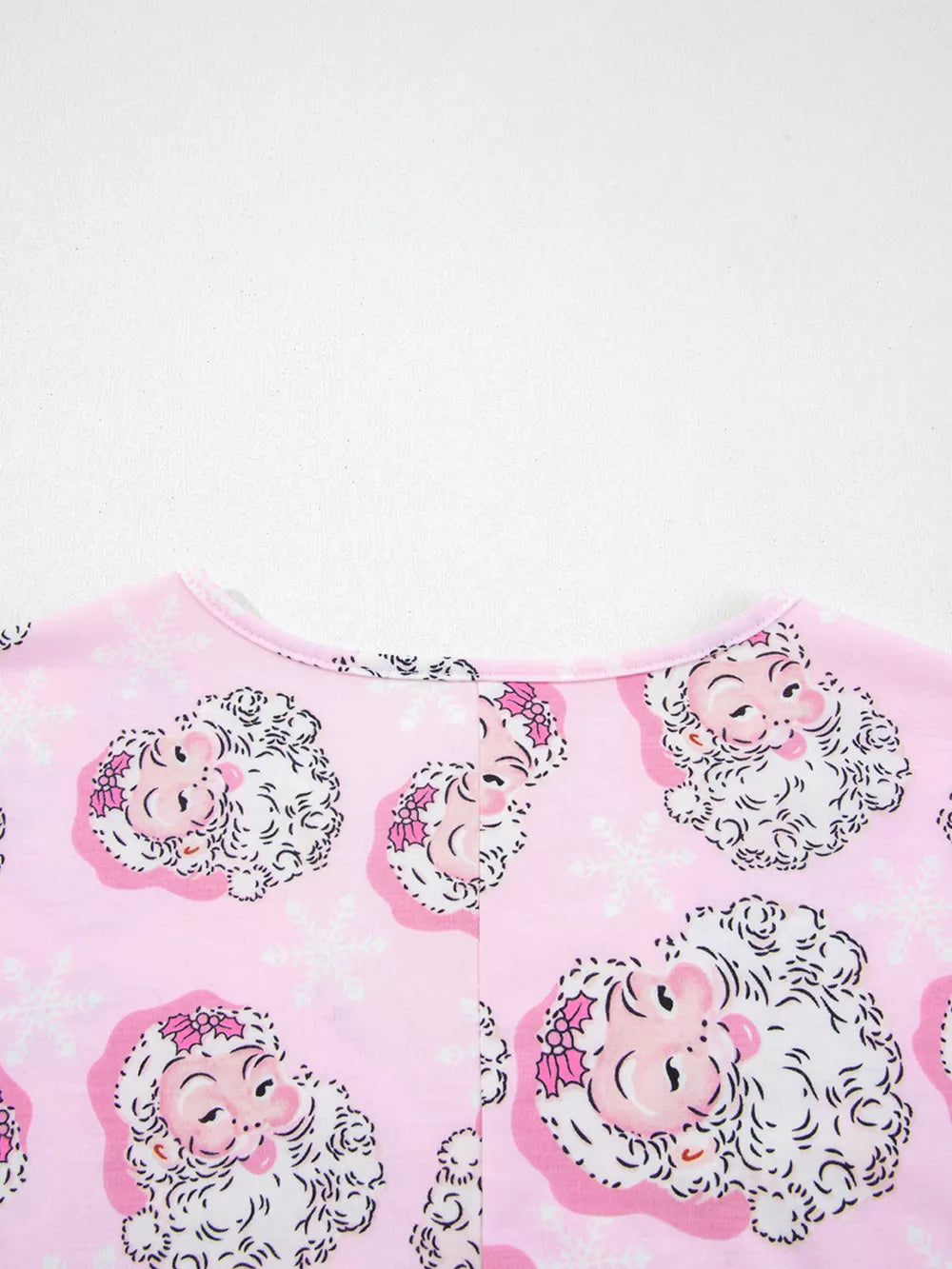 Pink V-neck pajama top with a festive Santa Claus and snowflake print.