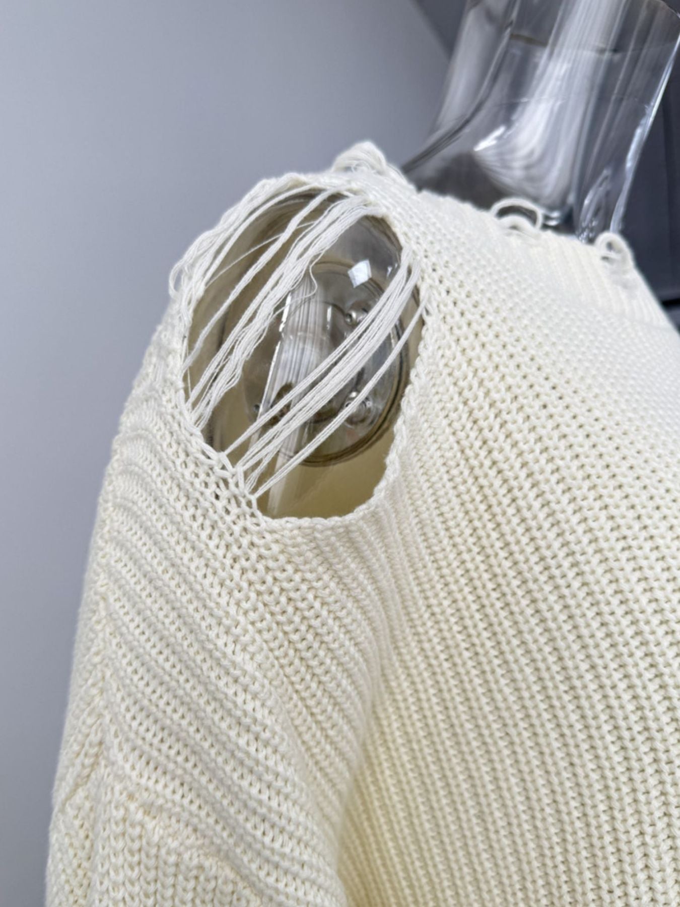 Off white distressed cotton sweater with deconstructed shoulder detail and frayed threads.