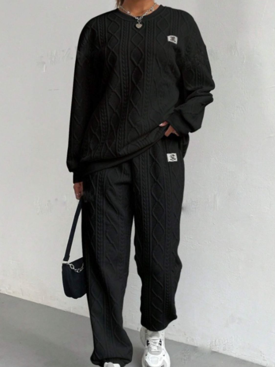 Black cable knit loungewear set with crew neck sweater and wide leg pants.