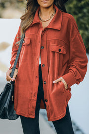 Fleece shirt jacket in orange with patch pockets and button front.