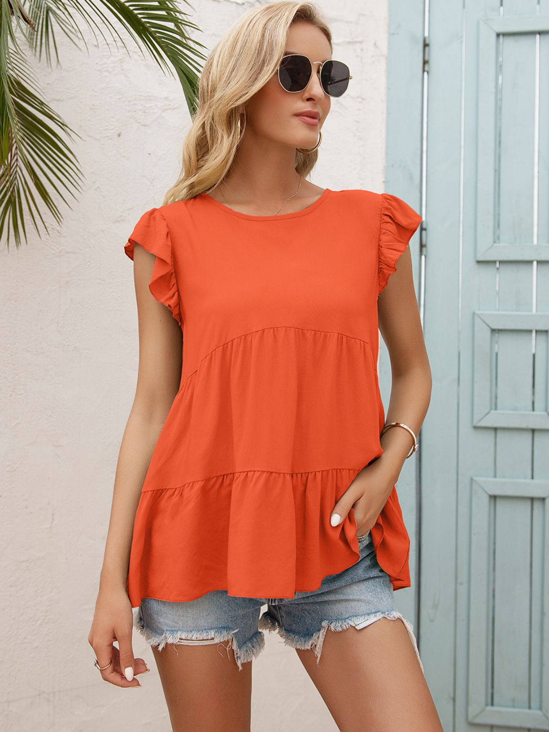 Orange babydoll blouse with ruffled sleeves and tiered hem.