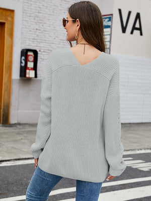 Light grey ribbed knit sweater with V-neck and subtle sleeve detail.