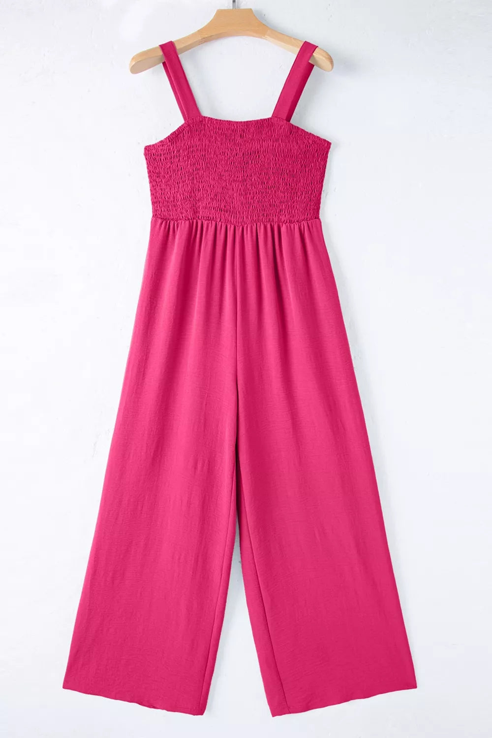 Smocked bodice romper in deep rose with wide legs and adjustable straps.
