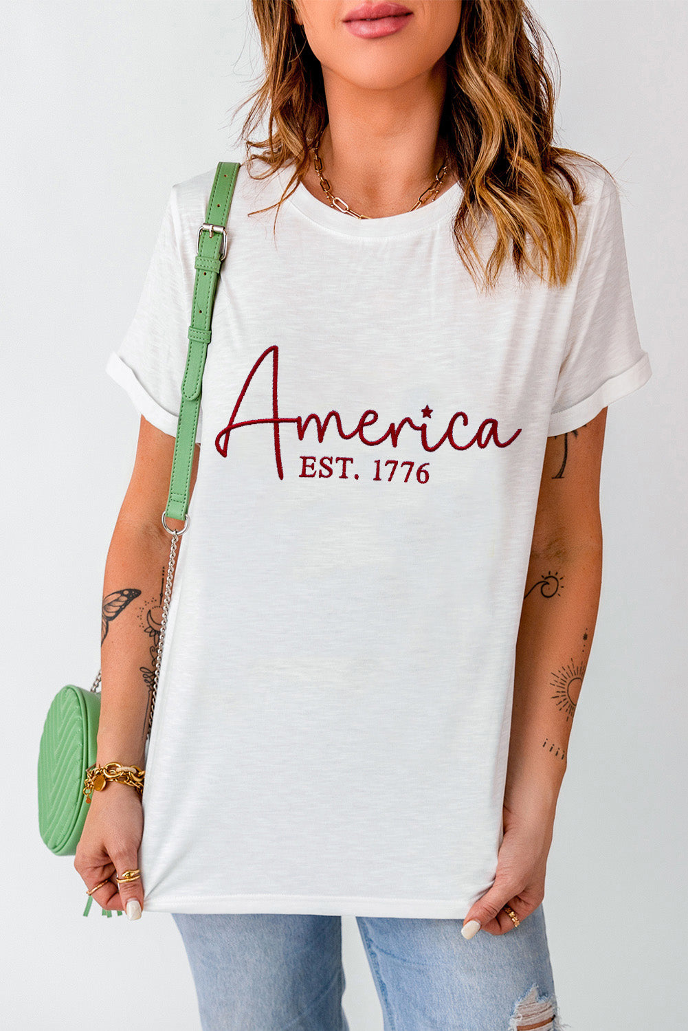 White graphic t-shirt with "America EST. 1776" in burgundy script.