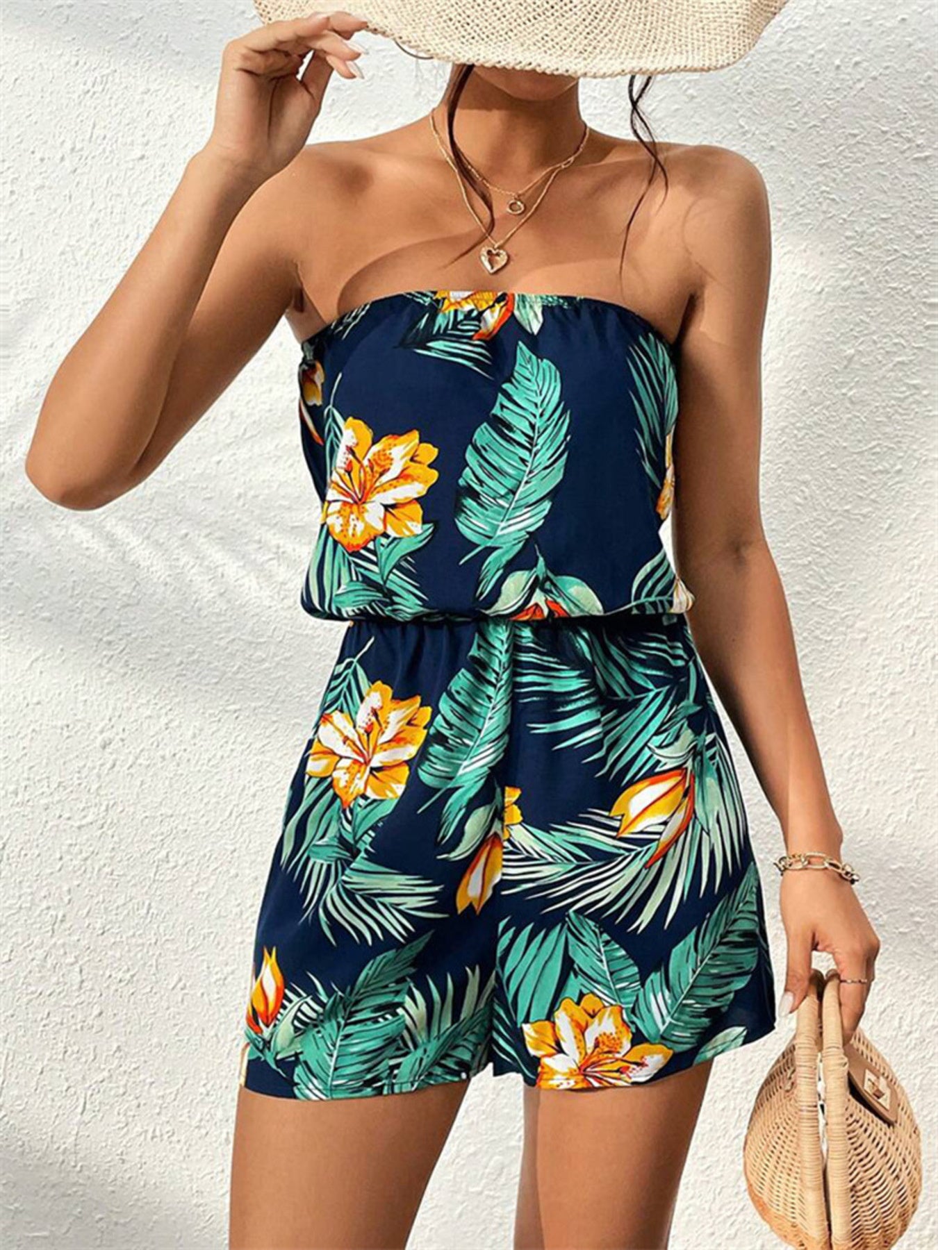 Strapless navy romper with tropical floral and leaf print, blouson top, and short legs.