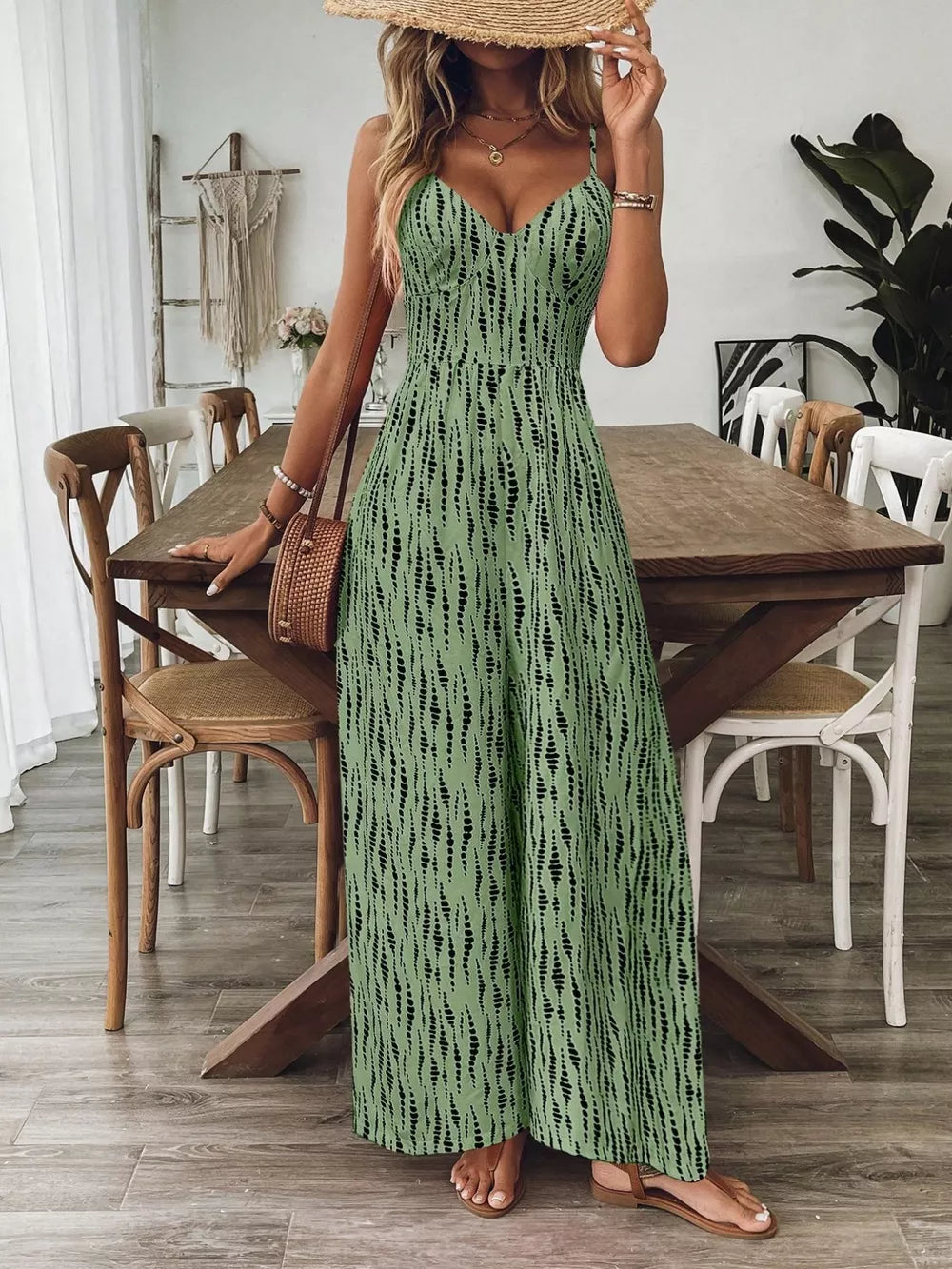 Matcha green wide-leg jumpsuit with black abstract print, V-neck, spaghetti straps, and smocked bodice.