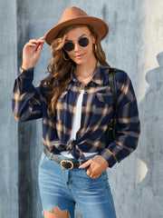 Plaid button-up shirt in dark blue with tan and white plaid, featuring chest pockets and a knotted hem.