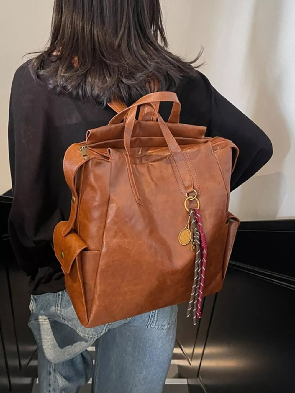 Terracotta leather convertible backpack with side pockets and keychain detail