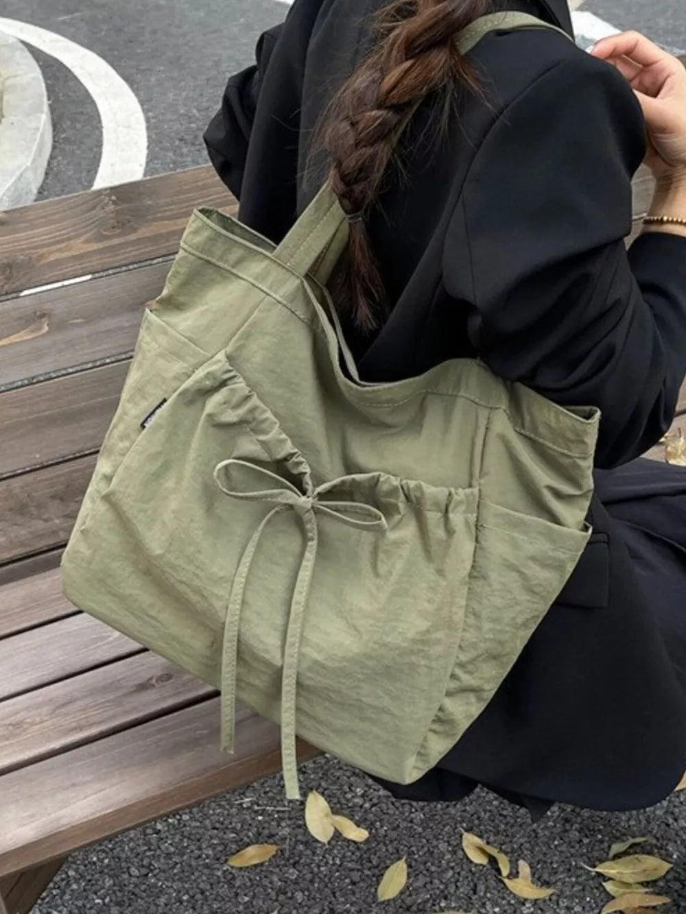 Olive green nylon tote bag with drawstring closure and bow detail.